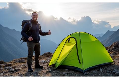 Liam K. standing proudly next to his tent in a rugged mountain landscape.